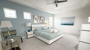 A bedroom with a bed, nightstands, a chair, a table, a ceiling fan, and a refrigerator. - Update Providence golf • Lexurey Villa cul-de-sac • Near Disney
 (Davenport)