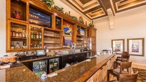 A bar area with wooden shelves stocked with bottles and glasses, a granite countertop, and bar stools. - Update Providence golf • Lexurey Villa cul-de-sac • Near Disney
 (Davenport)
