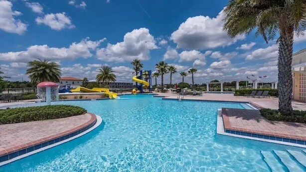 A large outdoor swimming pool with a yellow water slide, palm trees, and lounge chairs. - Update Providence golf • Lexurey Villa cul-de-sac • Near Disney
 (Davenport)