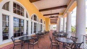 A covered outdoor patio with brick flooring, white columns, and multiple tables and chairs. - Update Providence golf • Lexurey Villa cul-de-sac • Near Disney
 (Davenport)