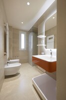 A modern bathroom with a toilet, bidet, and bathtub.