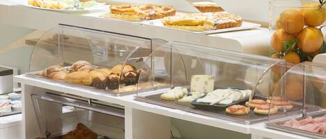 A buffet with various food items including pastries, fruits, and meats.