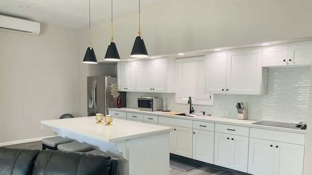 A modern kitchen with white cabinetry, a central island, and pendant lighting.
