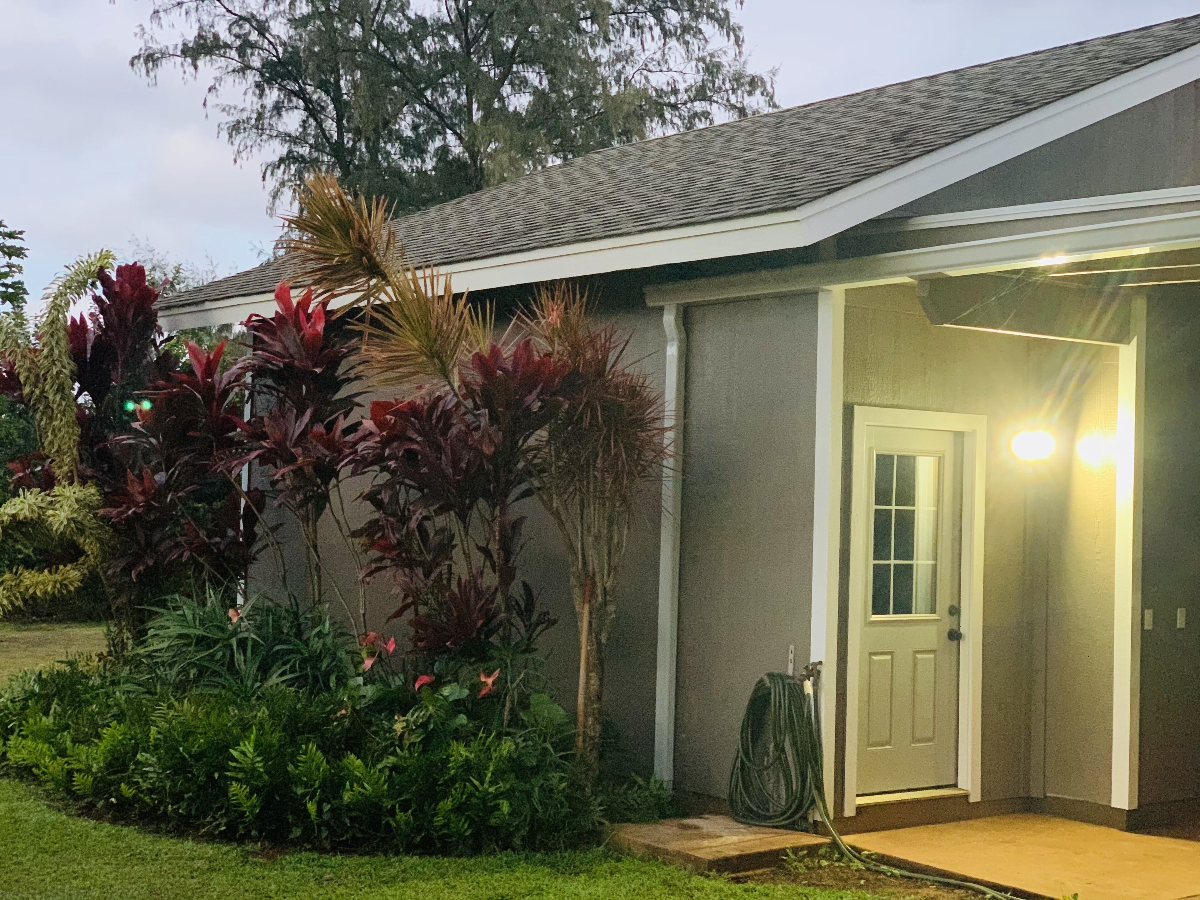 A residential building with a garage door, surrounded by lush greenery and a well-maintained lawn.