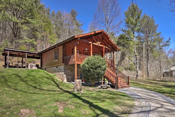 Eine Blockhütte mit Veranda, Treppe und einem kleinen Baum davor.