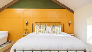 Een slaapkamer met een bed, een nachtkastje, een wandlamp en een raam.