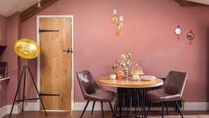 Een eethoek met een ronde houten tafel, twee stoelen, een vloerlamp en hangende lichtbollen.
