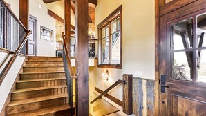 Una escalera de madera que conduce a una plataforma con una puerta y una ventana.