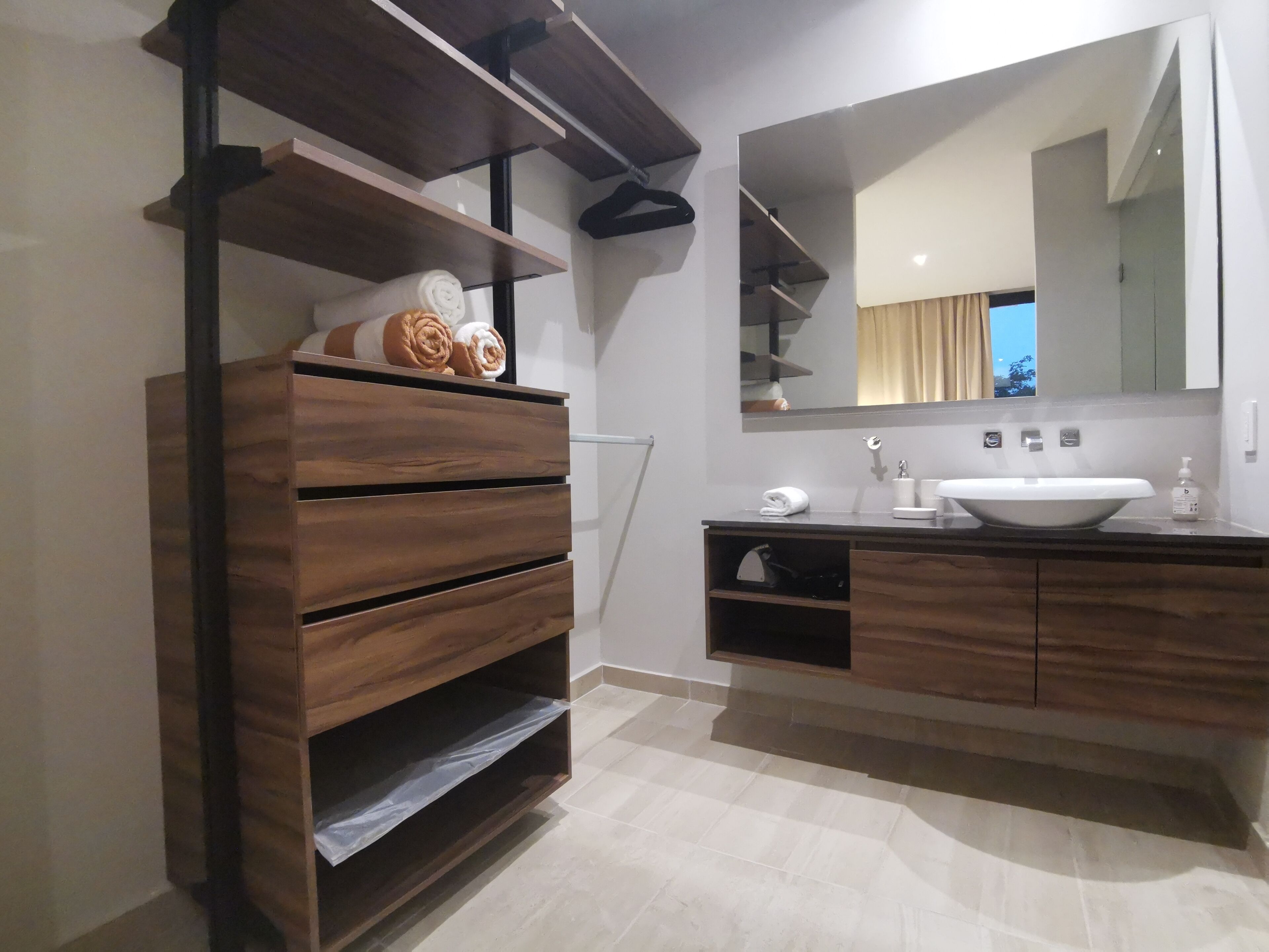 Un baño moderno con tocador de madera, un espejo grande y un lavamanos blanco.