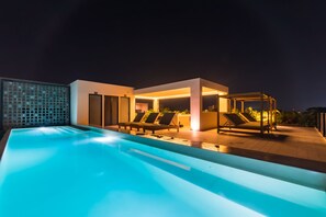 A modern outdoor pool area with lounge chairs and a covered seating area.