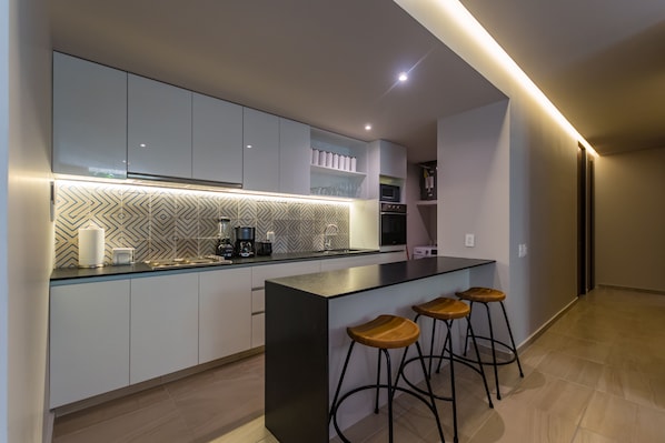 A modern kitchen with a central island, bar stools, and built-in appliances.