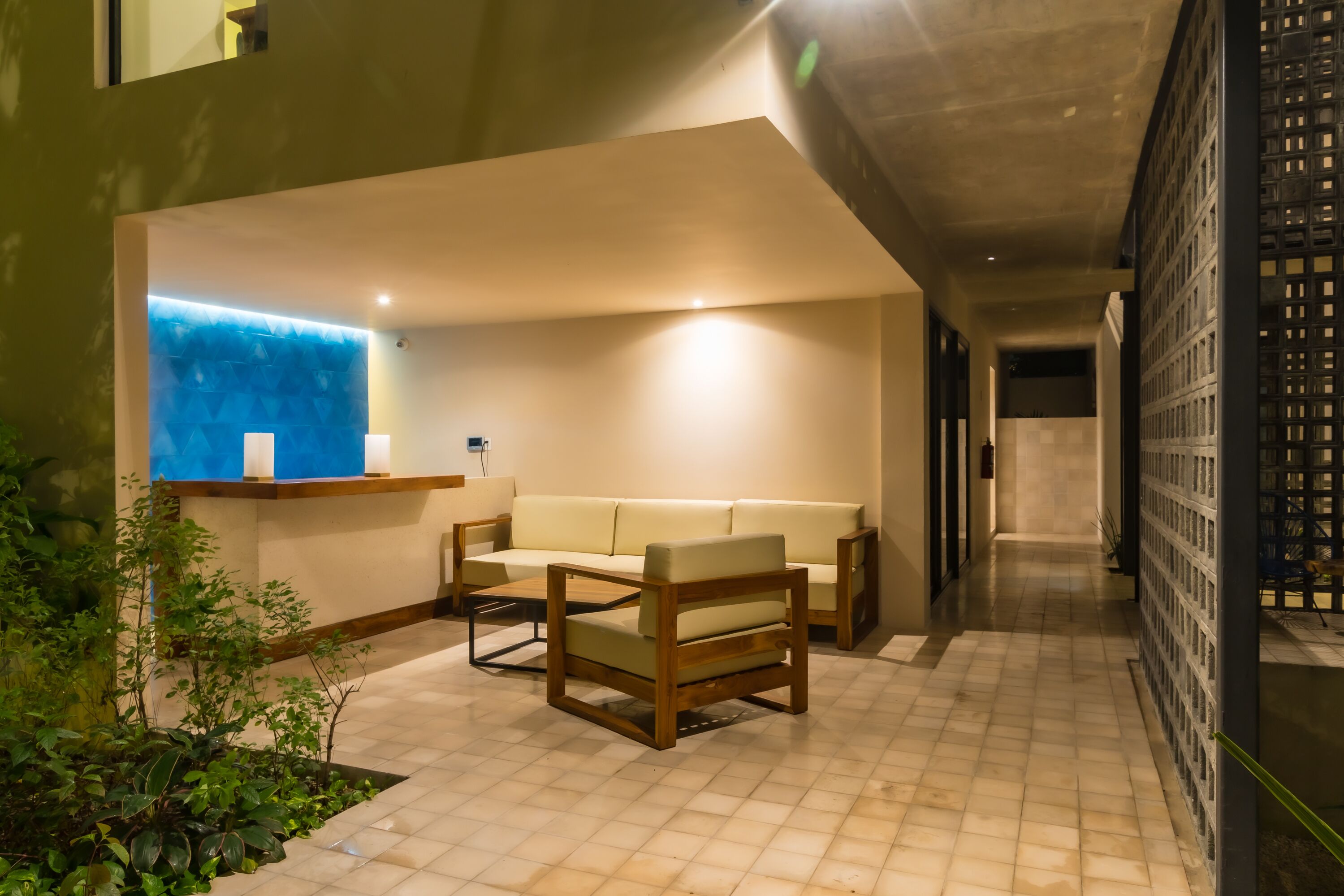 A modern interior with a sofa and chairs, a blue accent wall, and a tiled floor.