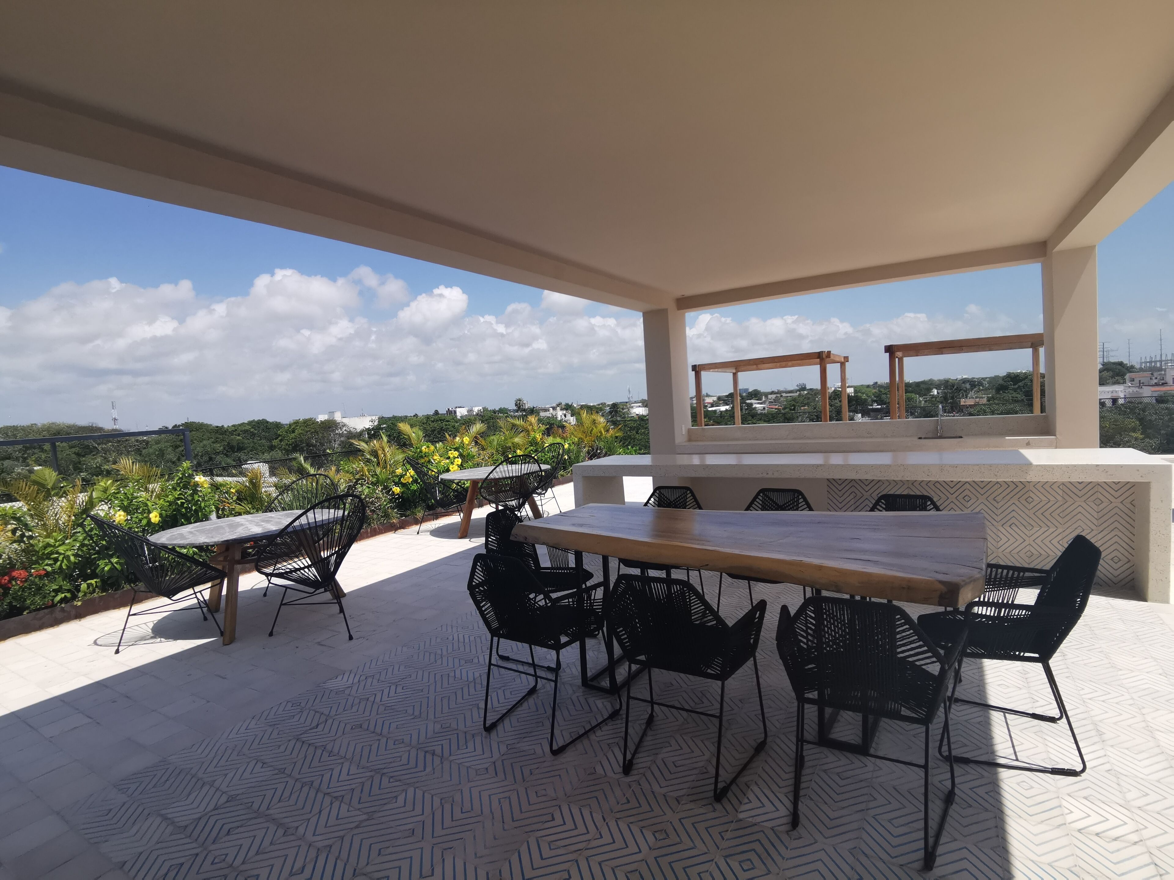 An outdoor patio with a dining table and chairs, a view of the city, and a large window.