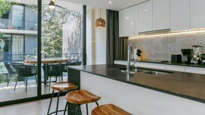 Una cocina moderna con una isla grande, taburetes de bar y un comedor con sillas.