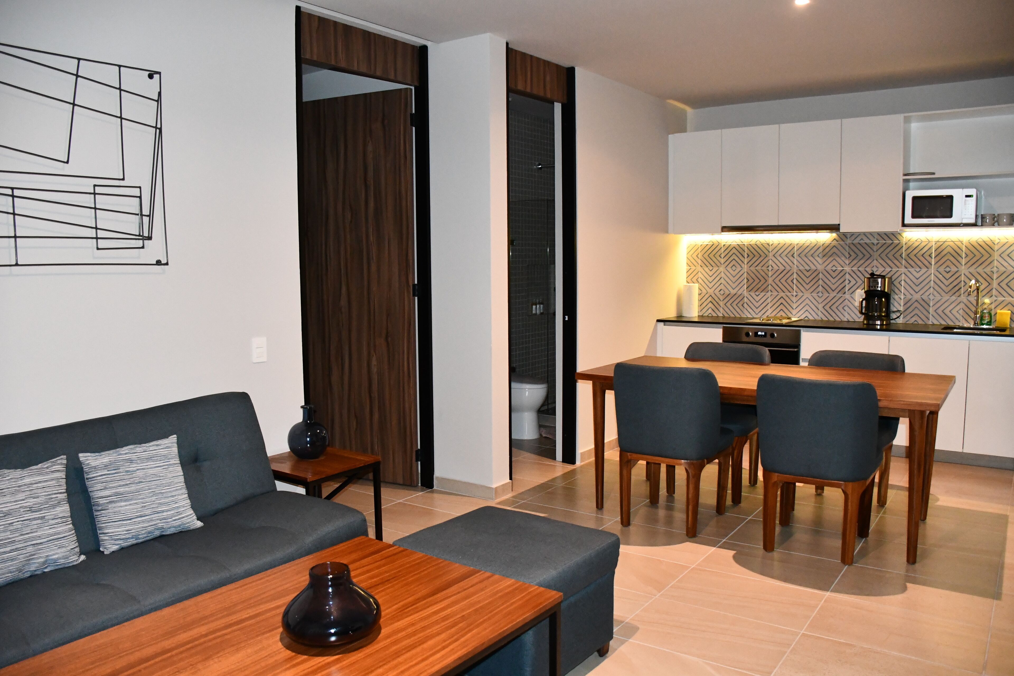 A modern living room with a sofa, coffee table, and dining area with chairs.