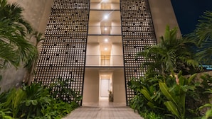 Un edificio moderno con fachada geométrica, entrada central y zonas verdes circundantes.