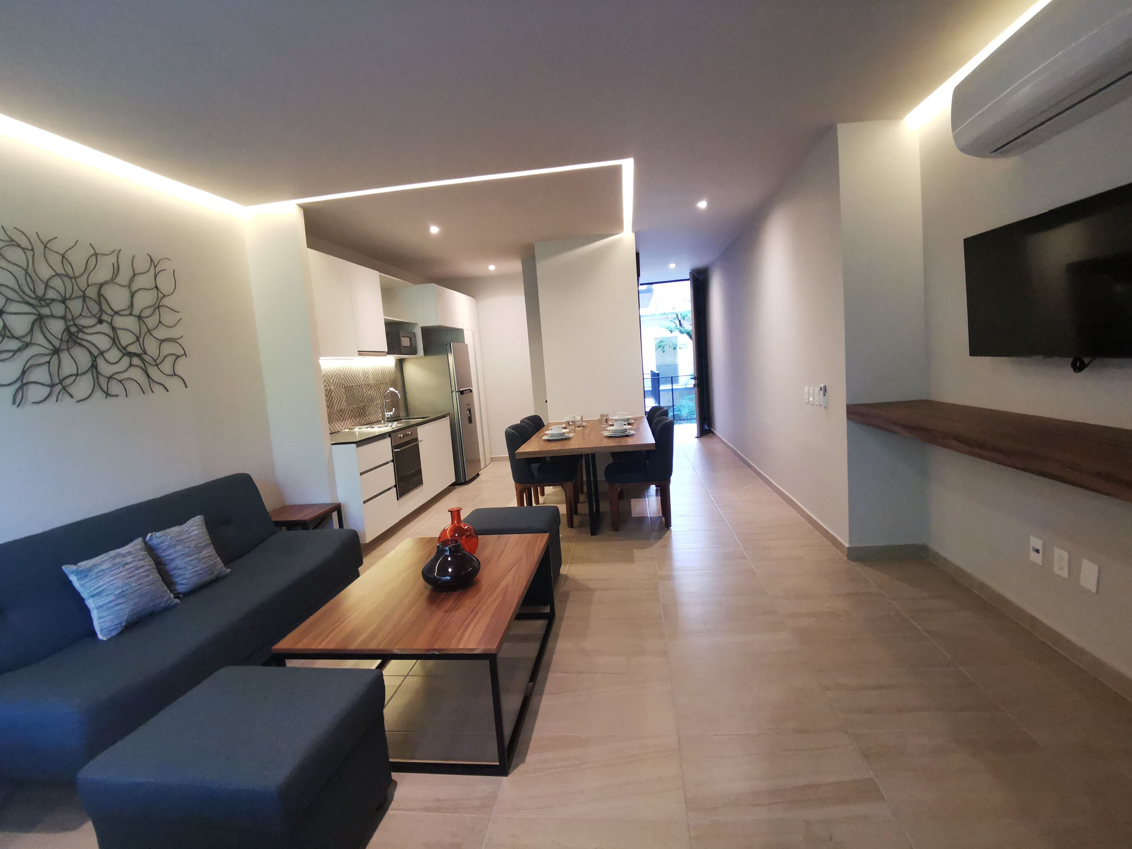 Ein modernes Wohnzimmer mit einer Couch, einem Couchtisch und einem an der Wand befestigten Fernseher.