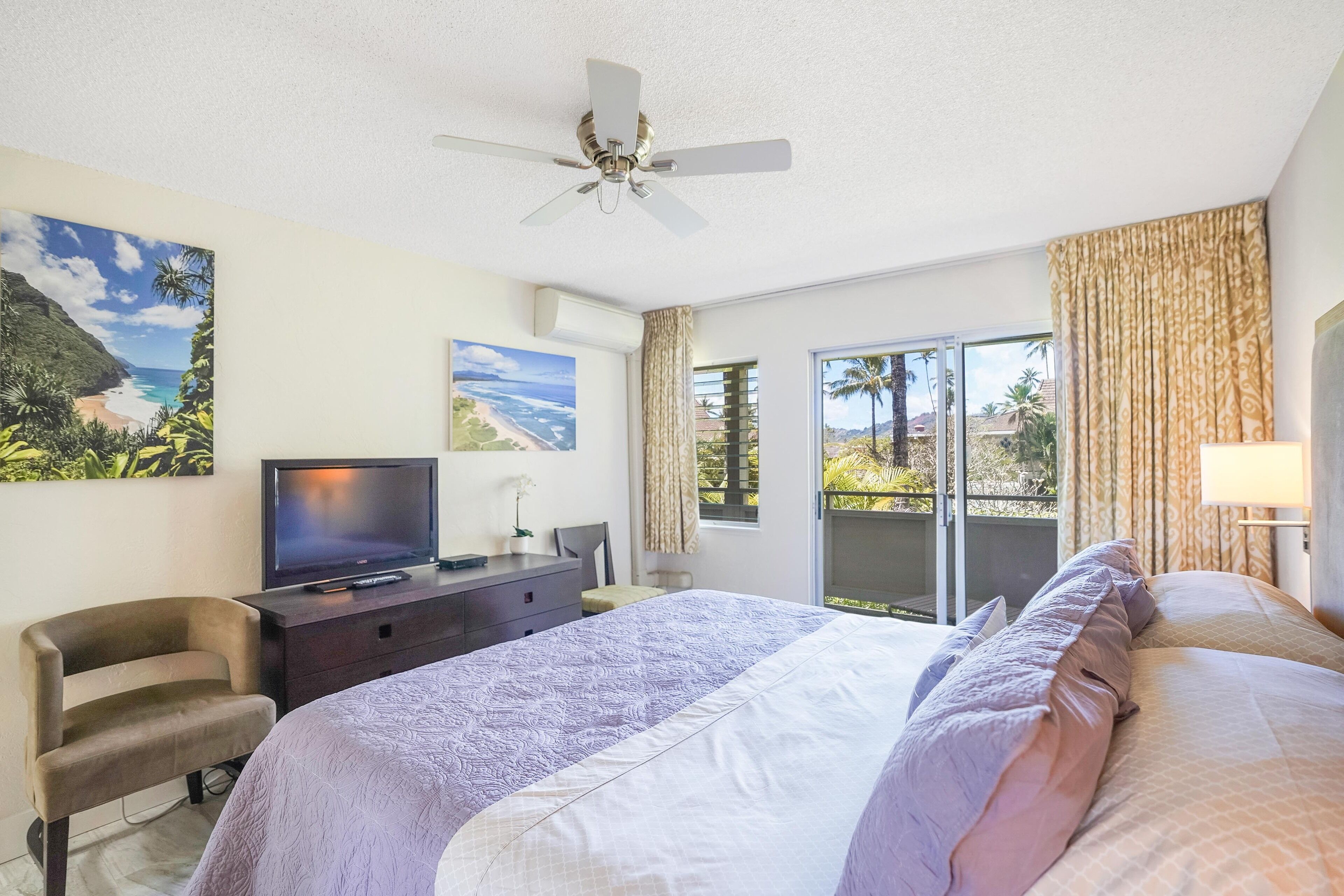 Une chambre d’hôtel comprenant un lit, un bureau avec une télévision, un ventilateur de plafond et une vue sur l’extérieur grâce à une porte coulissante.