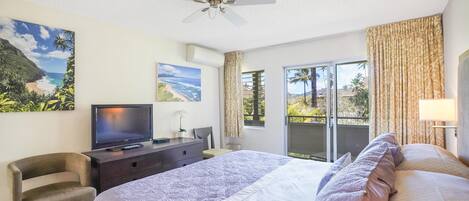 Une chambre d’hôtel comprenant un lit, un bureau avec une télévision, un ventilateur de plafond et une vue sur l’extérieur grâce à une porte coulissante.