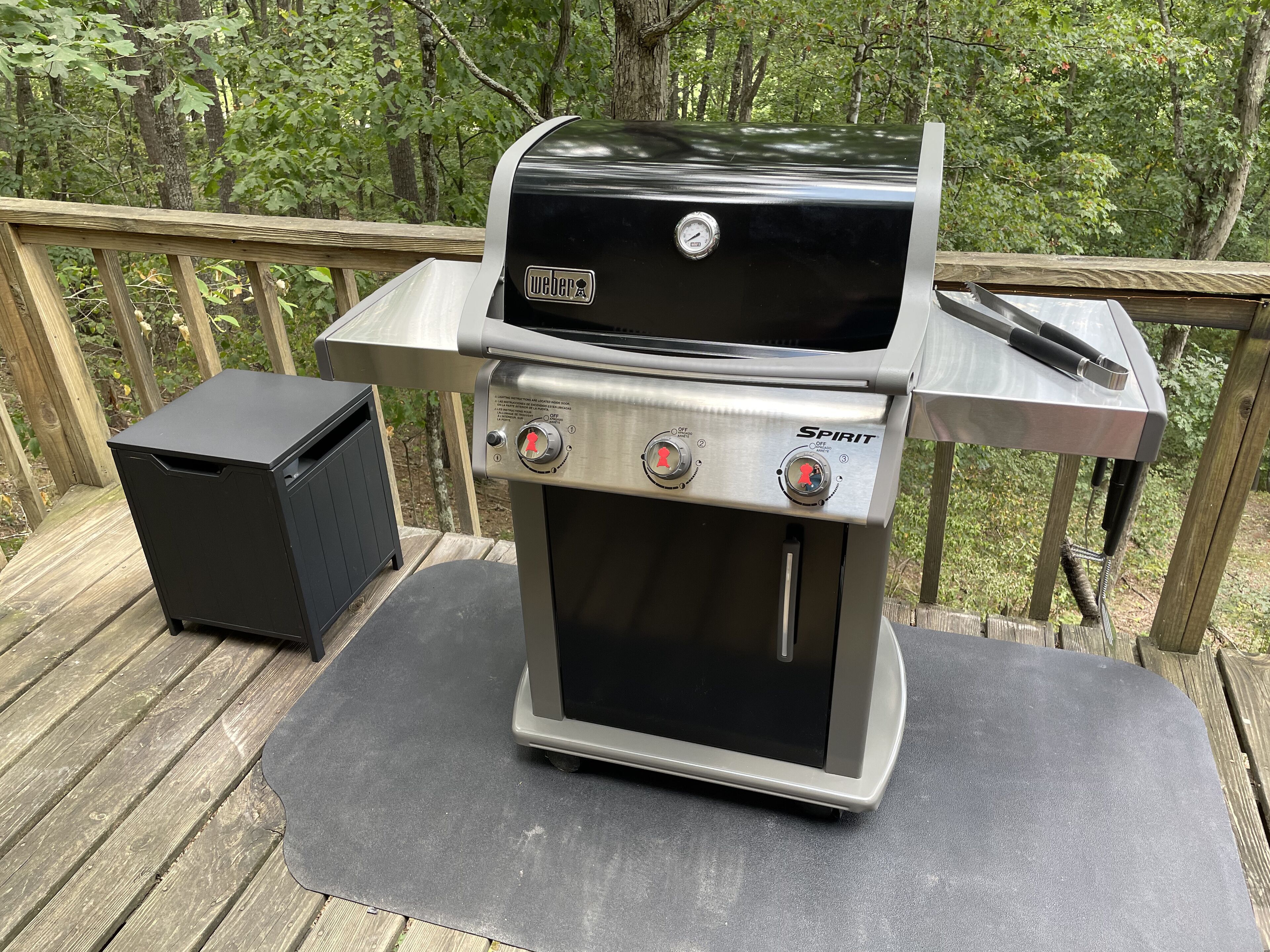 Un barbecue Weber Spirit portable, doté d’un thermomètre numérique, placé sur une terrasse en bois.
