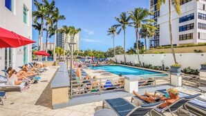 A poolside area with lounge chairs, a swimming pool, and palm trees. - 5 Stars Apart-Suites by Hilton. Amazing views. (Fort Lauderdale)