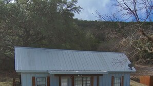 Un petit bâtiment d’un seul étage, doté d’un toit en métal, d’un porche à l’avant et d  ’une allée en gravier.
