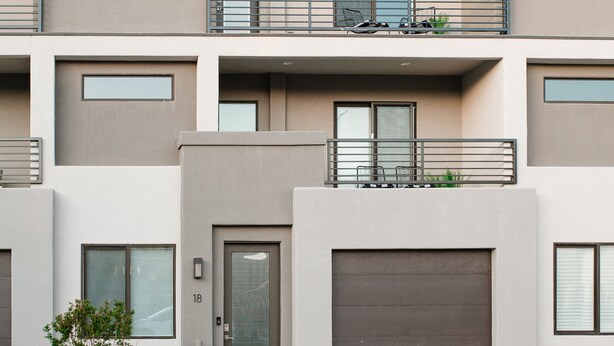 Een modern woongebouw met meerdere verdiepingen, een plat dak, grote ramen en een garage.
