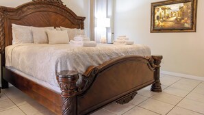 Un grand lit en bois richement décoré, doté d’une tête de lit, de plusieurs oreillers et de serviettes soigneusement pliées.