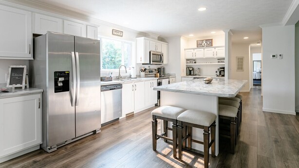 A modern kitchen with white cabinetry, stainless steel appliances, and a marble island with bar stools. - Beautiful Canandaigua Lake view - Family friendly! 4 Season Home - Fall Foliage! (Canandaigua)