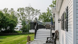 A covered outdoor deck with stone steps leading to a seating area with chairs and a table. - Beautiful Canandaigua Lake view - Family friendly! 4 Season Home - Fall Foliage! (Canandaigua)