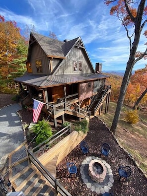 A rustic cabin with a porch, a fire pit, and an American flag. - Tranquility Perch | 3-State Mtn Views + Hot Tub (Murphy)