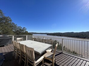 A deck with a table and chairs overlooking a river.