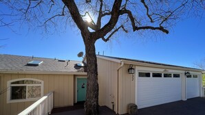 A two-story house with a green door, a garage, and a tree in front.