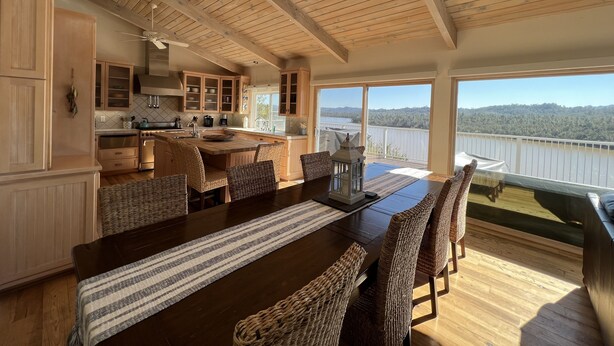 A spacious kitchen with wooden cabinets, a large island, and a dining area with wicker chairs.