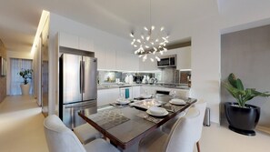 A modern kitchen with a central island, stainless steel appliances, and a contemporary light fixture.