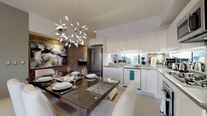 A modern kitchen with a dining area, stainless steel appliances, and a contemporary chandelier.