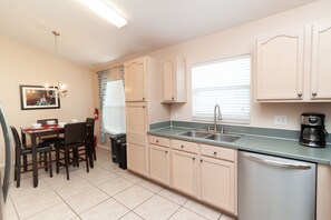 Enjoy meals in this kitchen with a dining table for four, featuring a dishwasher and stainless steel sink.