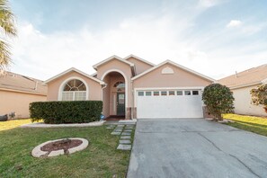 Stunning home with a central entrance, arched doorway, and a beautifully manicured lawn.