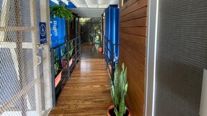 Een overdekte gang met houten vloeren, potplanten en een blauw bord dat een exclusief gebied aanduidt.