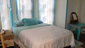 A bedroom with a bed, curtains, a small table, and a mirror. - #3 Bohemian Rest Place  (Watertown)