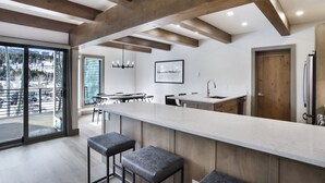 A modern kitchen with a large island, bar stools, and a view of the mountains through the sliding glass door. - 1 Block from Main Street, Free Shuttle, Walk To Gondola, Nightlife, Shopping (Breckenridge)