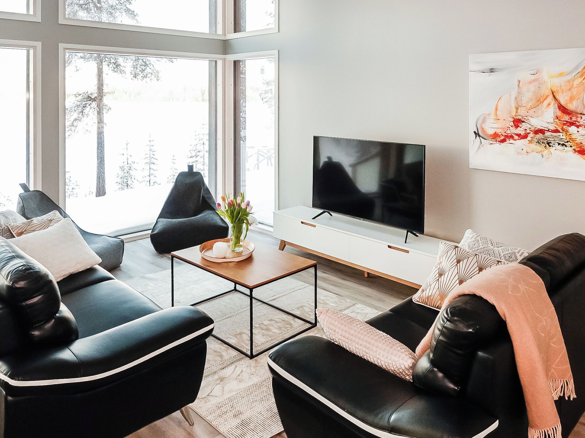 A modern living room with a sofa, coffee table, and a TV on a white cabinet.