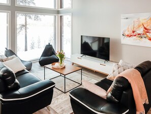 Een moderne woonkamer met een bank, salontafel en een tv op een witte kast.