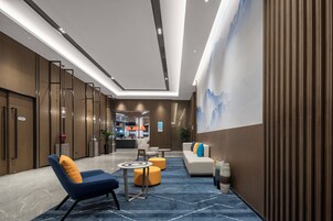 A modern lobby with a reception desk, seating area, and a large wall mural.