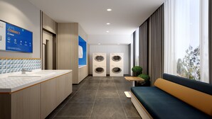 A modern hotel lobby with a reception desk, a large blue sign, a seating area, and two wall-mounted washing machines. - Holiday Inn Express Jingdezhen Ancient Town by IHG (Jingdezhen)