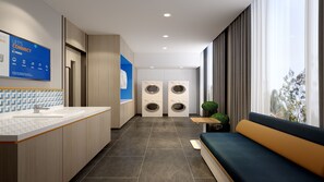 A modern hotel lobby with a reception desk, a large blue sign, a seating area, and two wall-mounted washing machines. - Holiday Inn Express Jingdezhen Ancient Town by IHG (Jingdezhen)