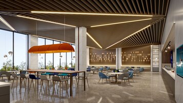 A modern interior with a high ceiling, linear light fixtures, and a seating area with tables and chairs.