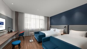 Una moderna camera d'hotel con due letti, una scrivania, una sedia e una televisione.