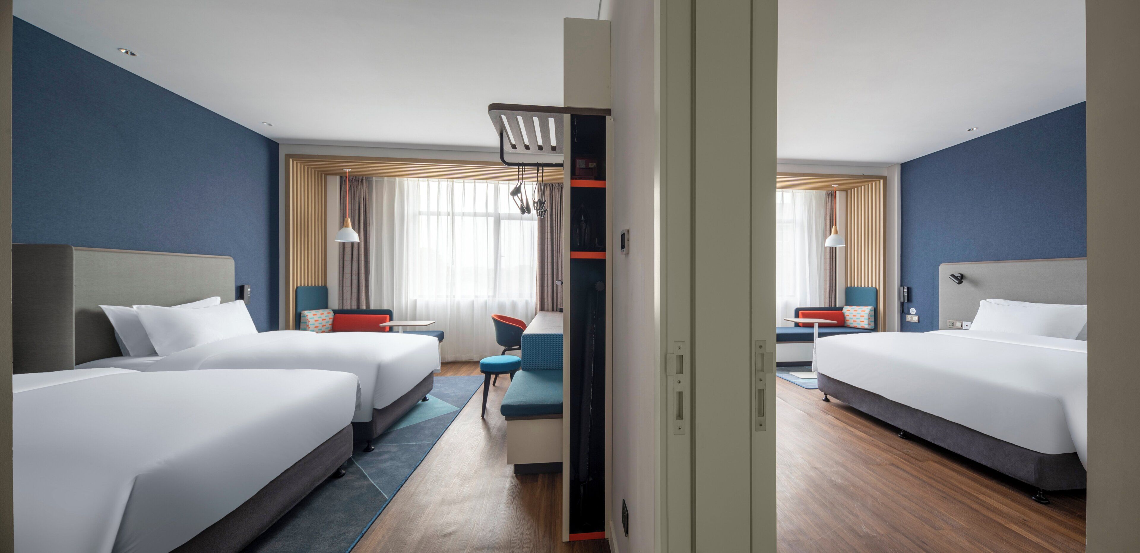 A hotel room with two beds, a seating area, and a view of the outdoors.