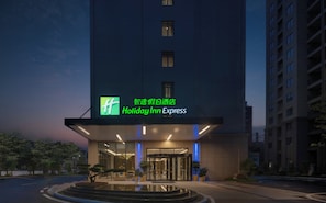 A Holiday Inn Express hotel entrance with a glass facade, a revolving door, and a small water feature in front. - Holiday Inn Express Jingdezhen Ancient Town by IHG (Jingdezhen)